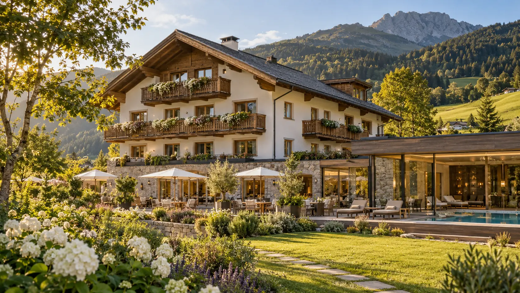 Das Hotel im Sommer: Chalet mit Holzbalkonen voller Blumen, Garten mit weißen Hortensien, dahinter grüne Berge